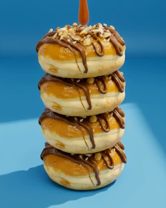 A stack of caramel-glazed Fresh Dough donuts drizzled with chocolate